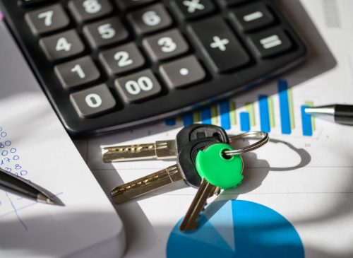 Calculator, keys, and financial documents on a desk